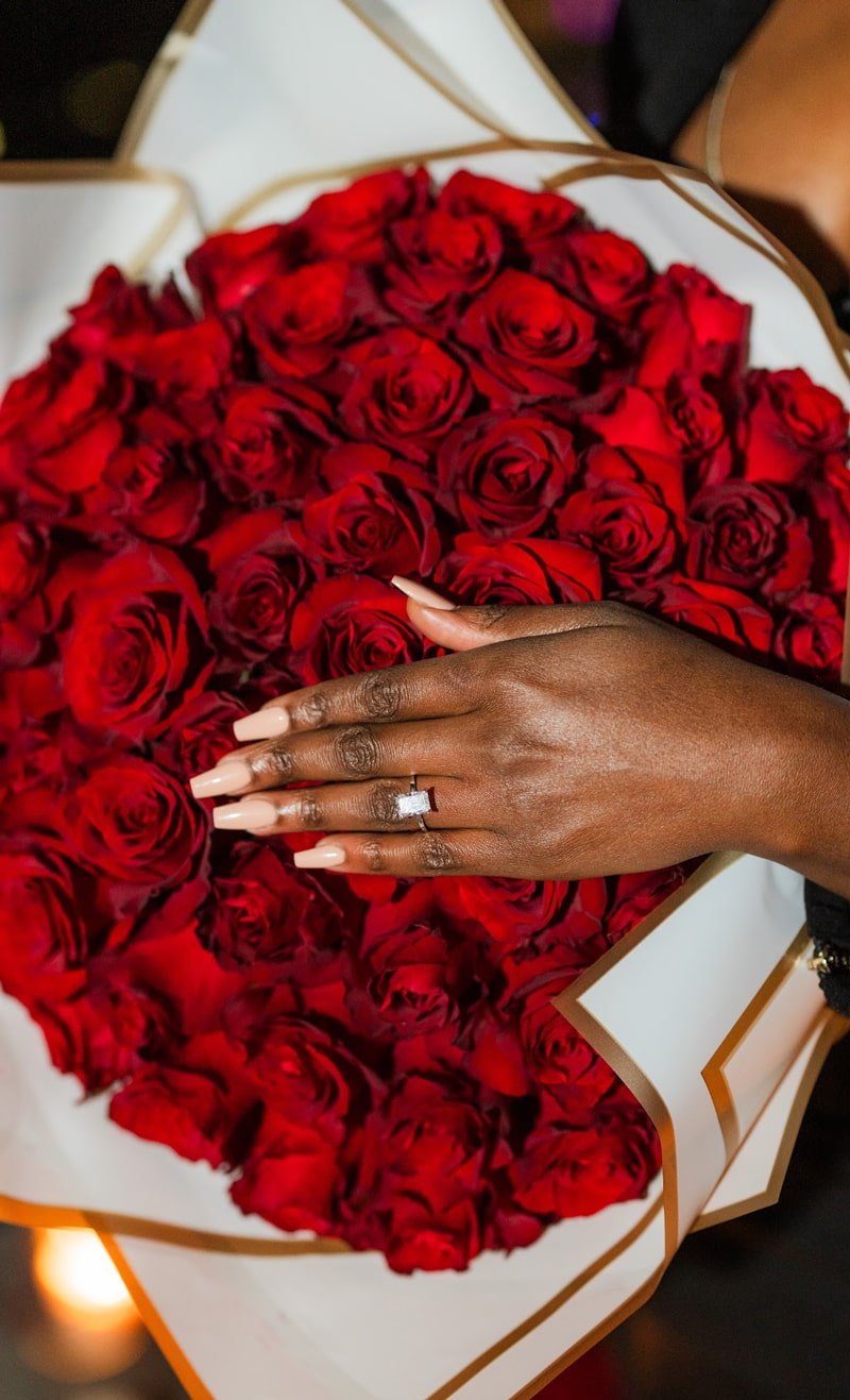 Custom Diamond Engagement Ring on a hand ontop of a bed of roses